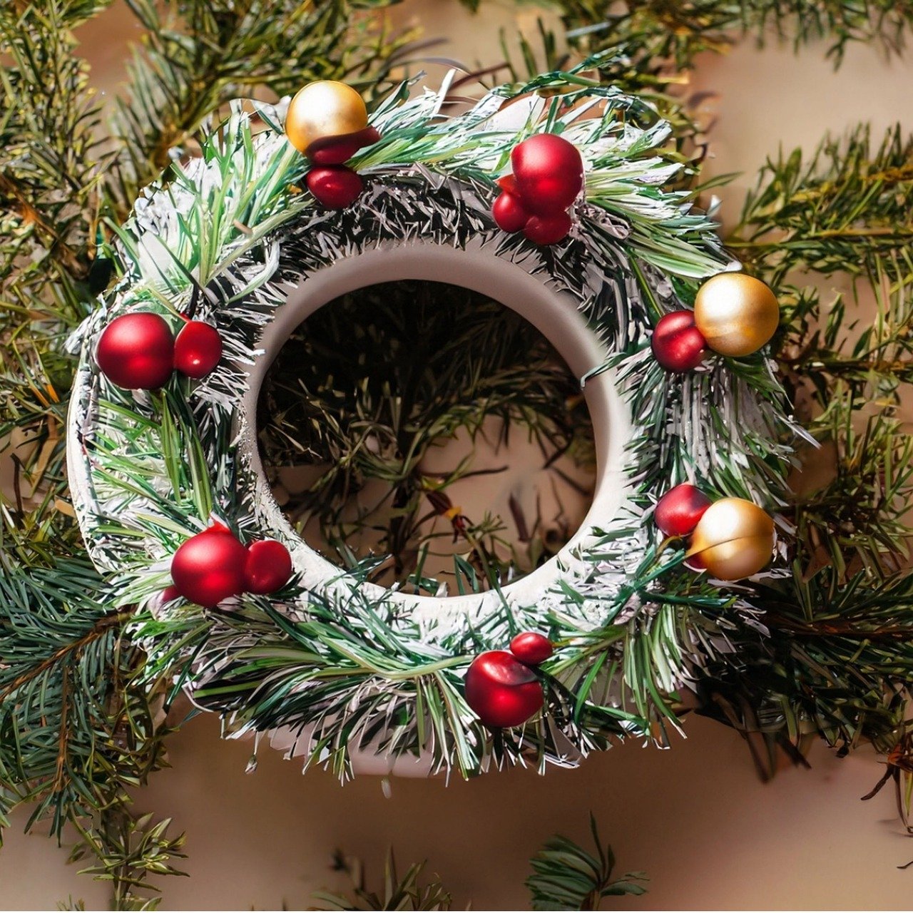 White circle wreath decorated with fir branches and red balls