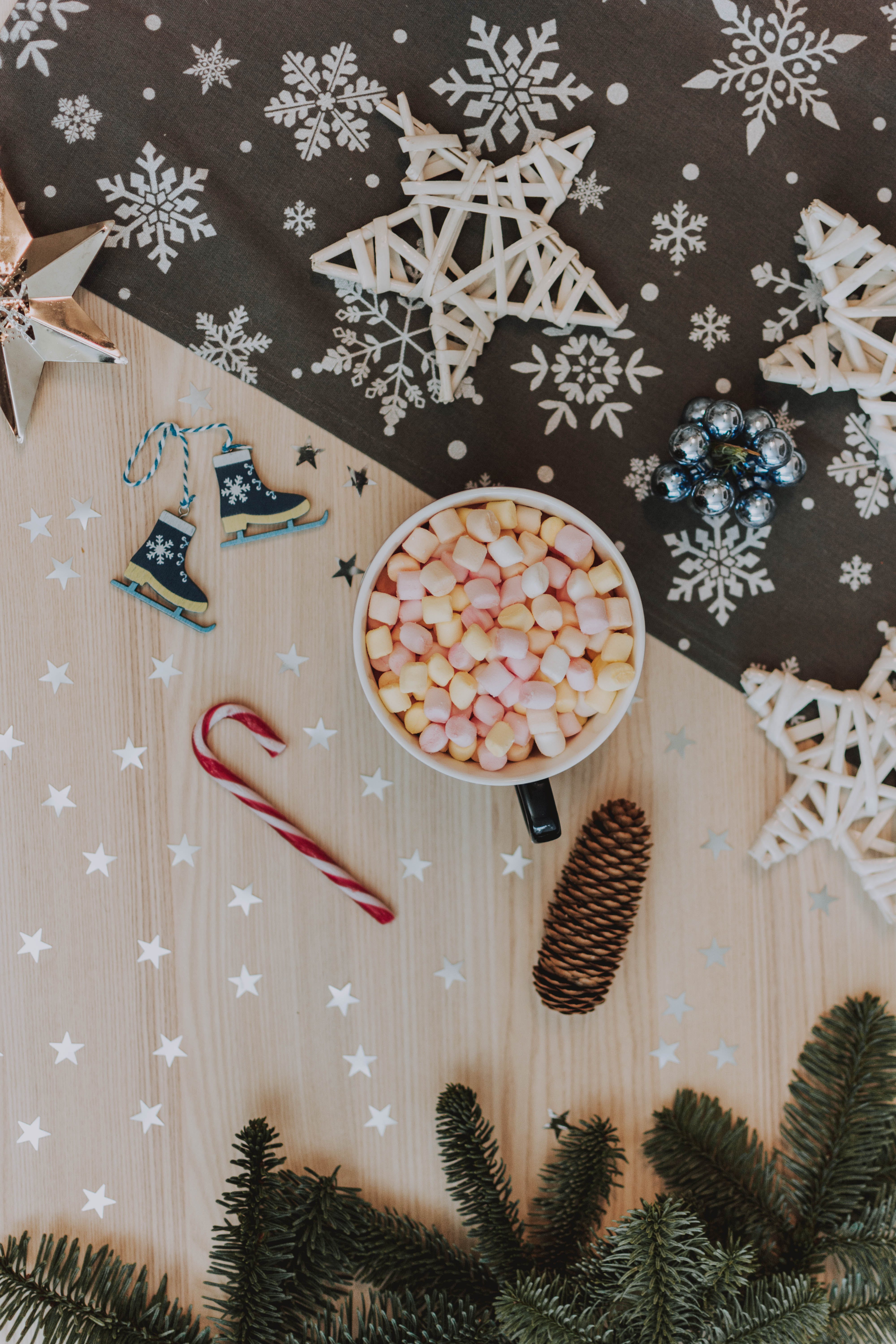 There are decorative snowflakes, Christmas decorations and a mug with marshmallows on the table