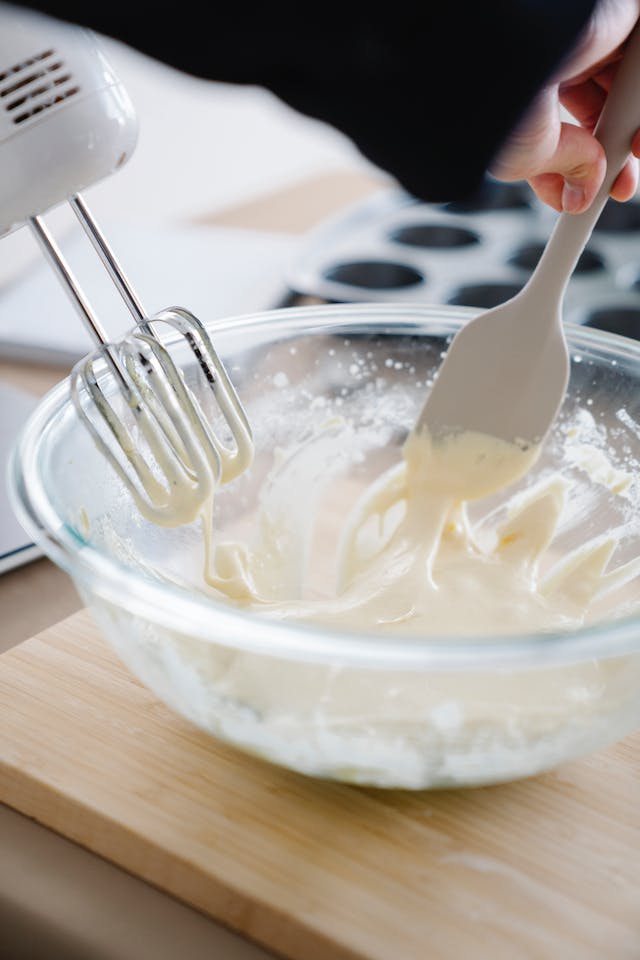 Mixer and spatula over bowl with cream