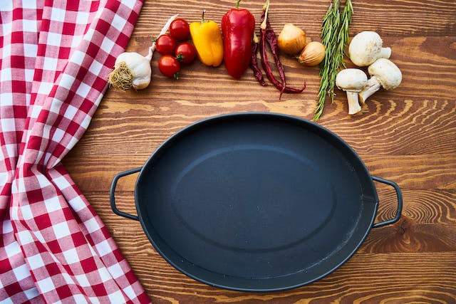  Checkered tablecloth, frying pan and vegetables on a wooden surface