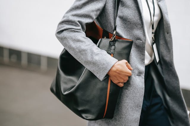 Woman in a gray raincoat with a black bag on her shoulder