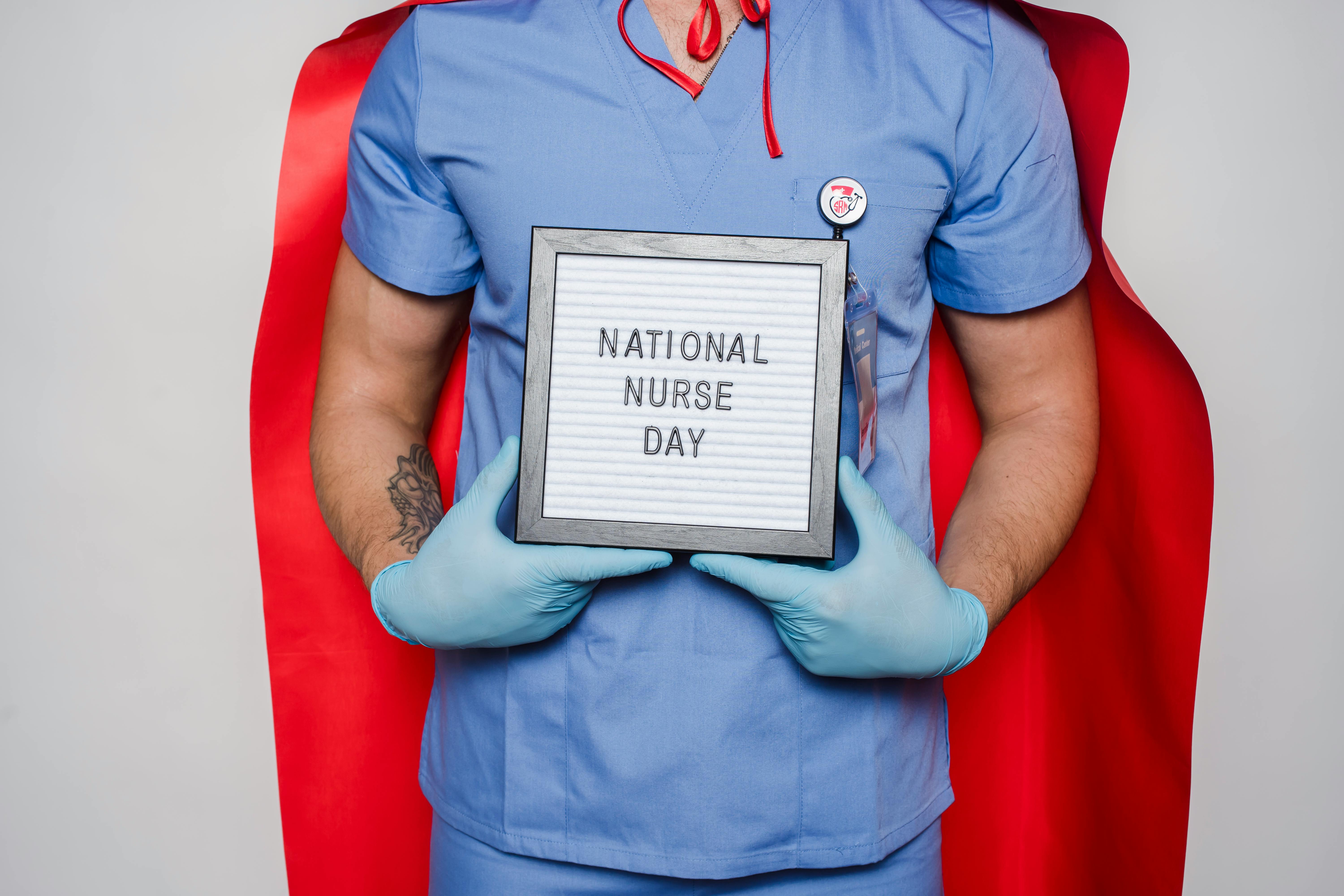 A man in a doctor's uniform holds a frame with the inscription NATIONAL NURSE DAY