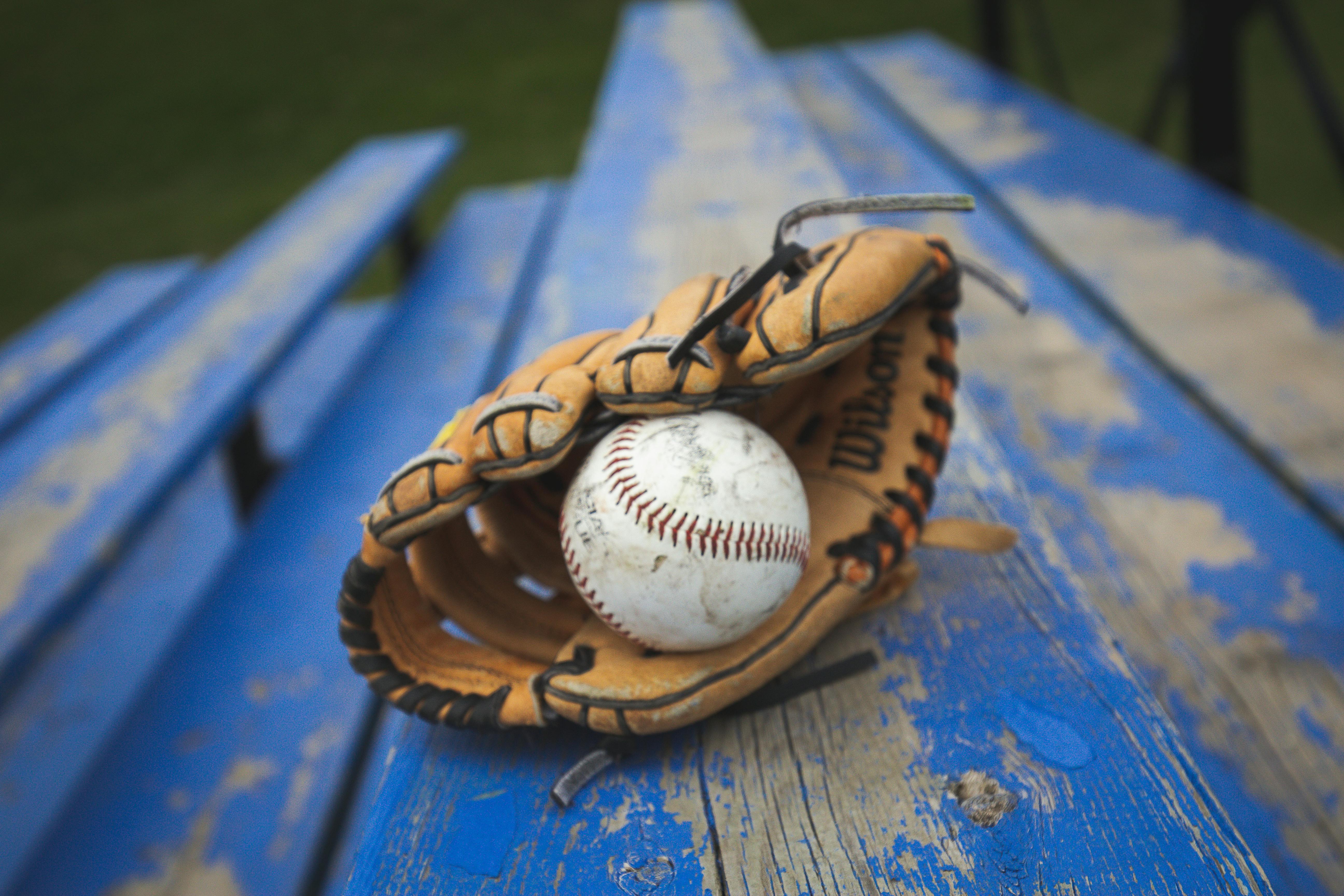 A baseball glove with a ball inside lies on a blue surface