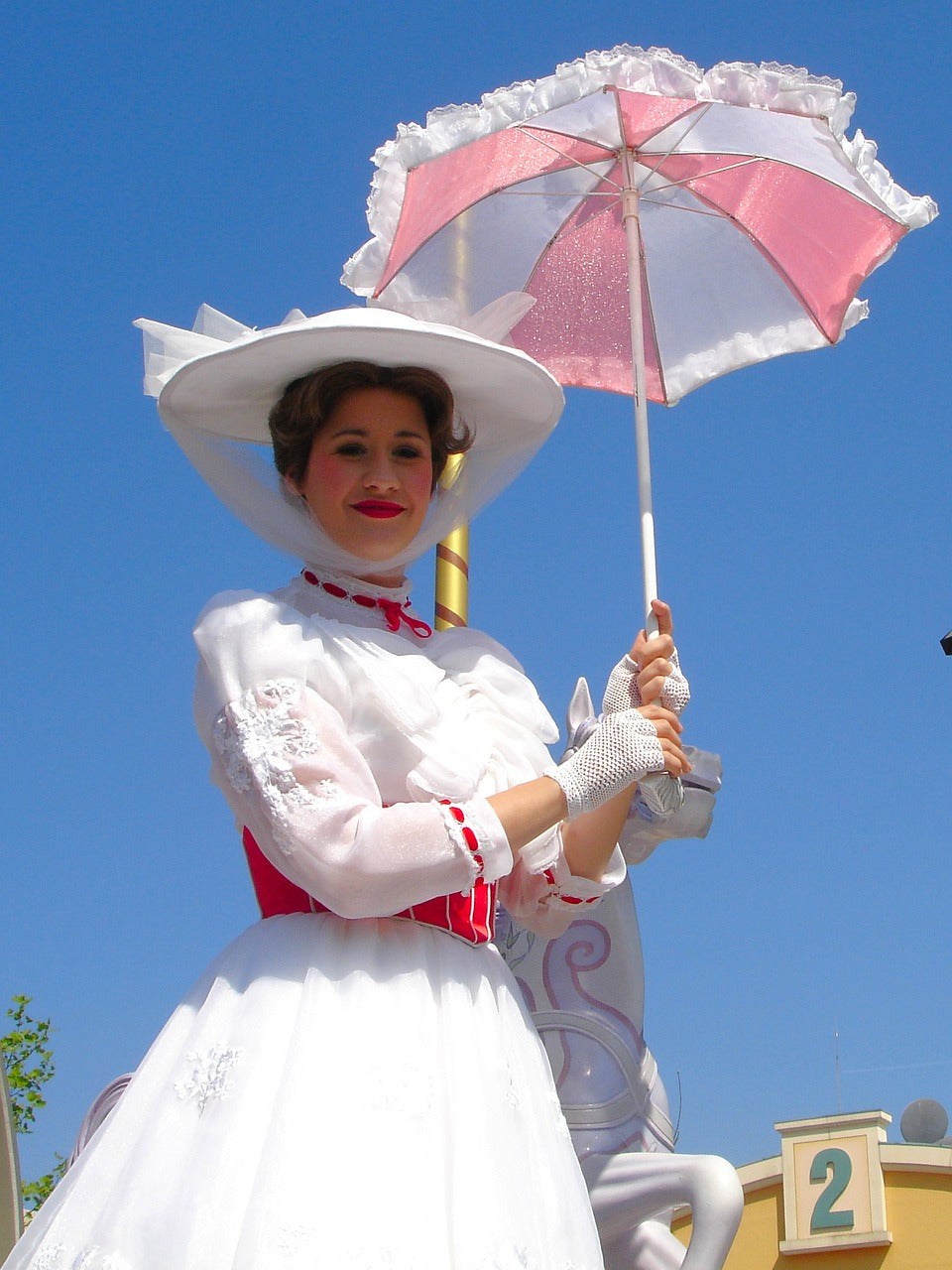 A woman in an aristocratic white dress with a red corset and an umbrella in her hands