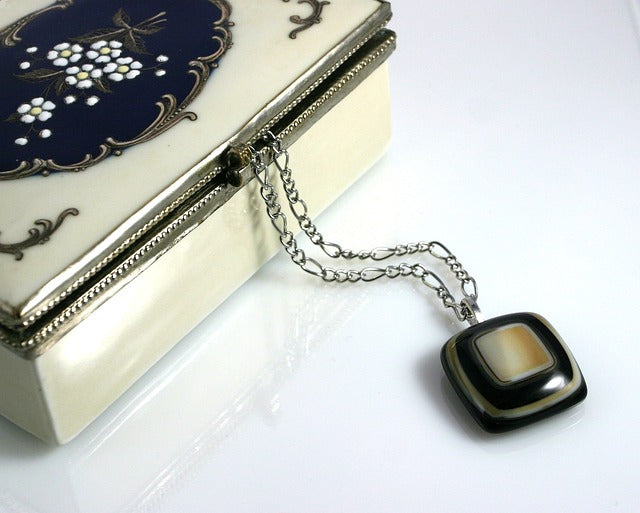 A pendant on a chain sticks out of a jewelry box