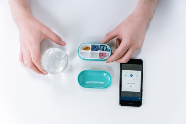 Glass of water, pill box and smartphone