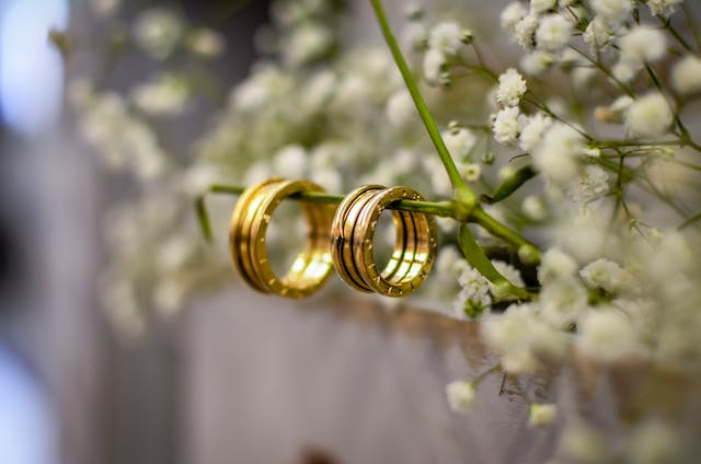 Two gold rings hang on a branch with flowers