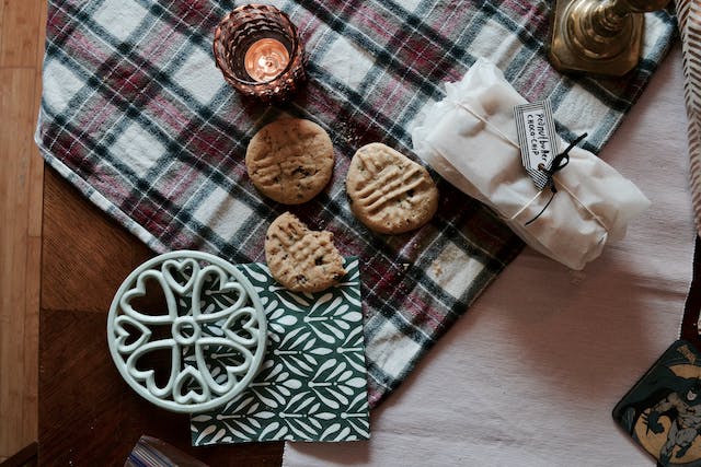 There are a glass and cookies on a checkered blanket