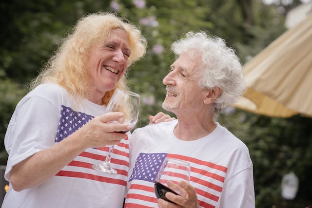 An elderly couple in T-shirts with the US flag and glasses in their hands