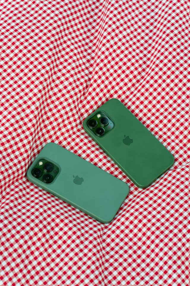 Two smartphones in green cases lie on a checkered blanket