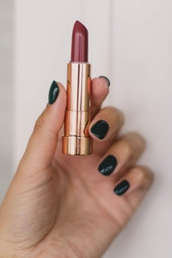 Hand with black nails holds lipstick