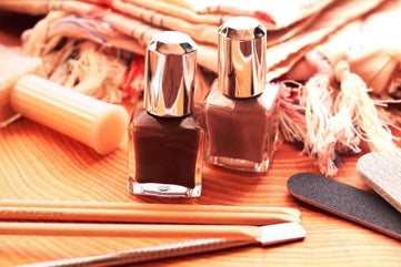 A manicure set and two bottles of nail polish on the table against the background of the bedspread