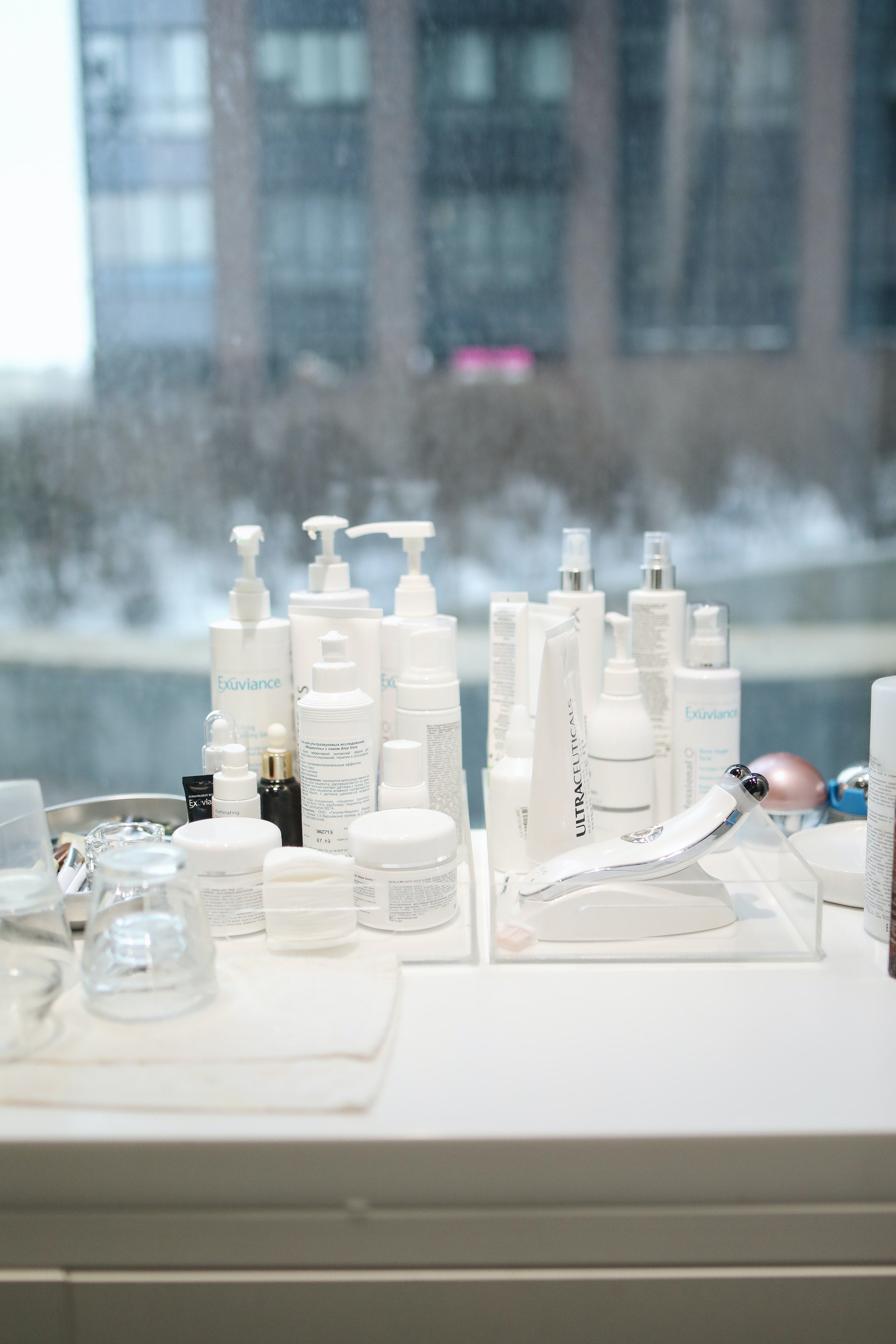 A set of cosmetic jars on a white windowsill in front of the window