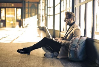 Man sitting on the floor by the window with a laptop