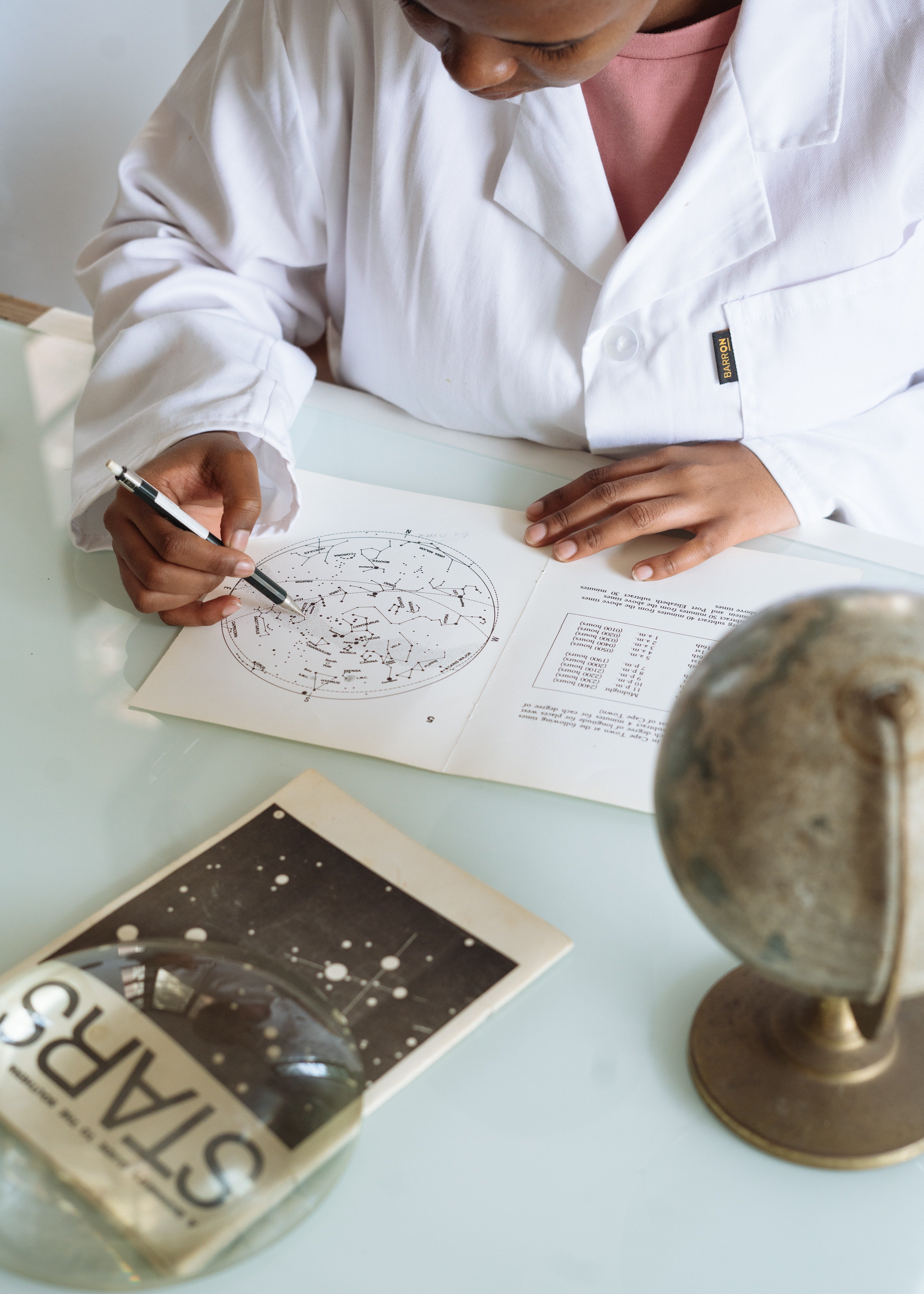 A woman in a medical gown writes with a pen on a sheet of pictures