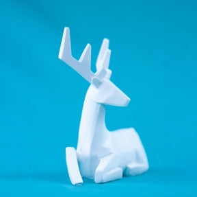 White figurine of a deer on a blue background