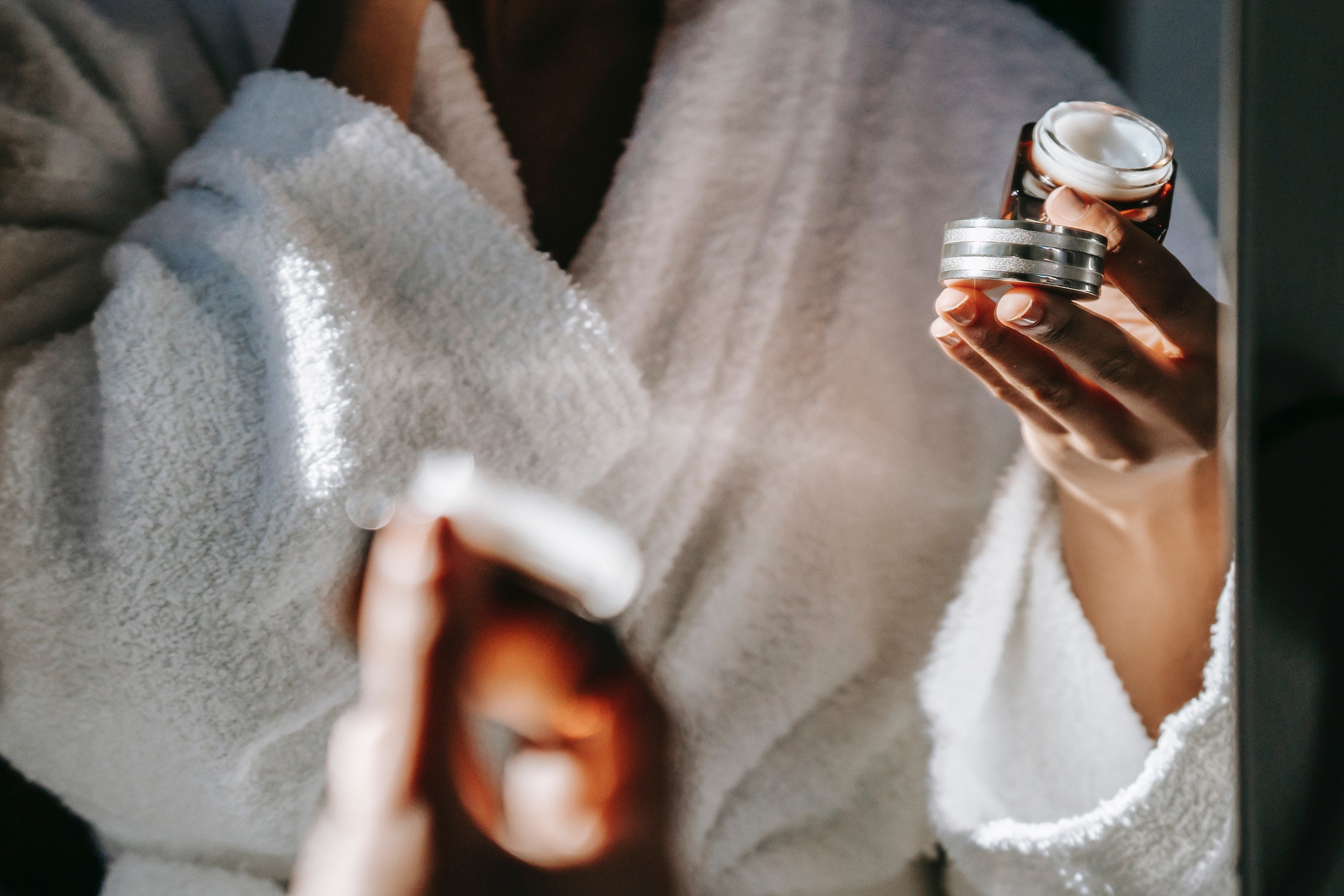 Woman in white bathrobe holding cream