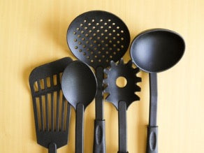 Black kitchen utensils on yellow background