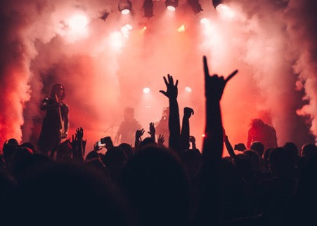 Dark silhouettes of hands on the background of the stage with musicians