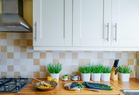 There are flowers in pots and dishes with food on the kitchen countertop