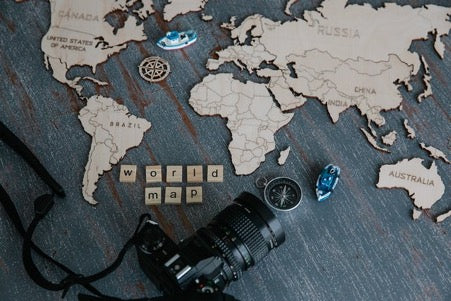 Continents made of wood and a camera lie on a wooden surface