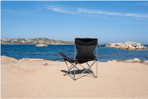 Camping chair stands on the shore of the lake