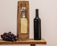 Wine bottle, gift bag and grapes on wooden table