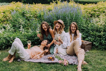 Four girls sit on a bedspread against a background of flowers