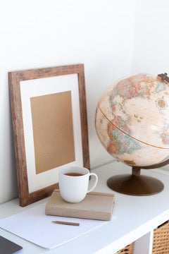 There is a photo frame and a globe on the shelf, and in front of the frame is a book with a mug on it