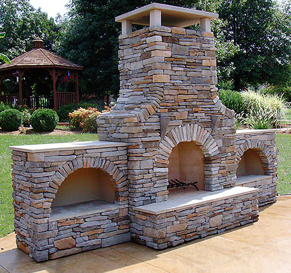 Full masonry stacked stone outdoor fireplace in a backyard.