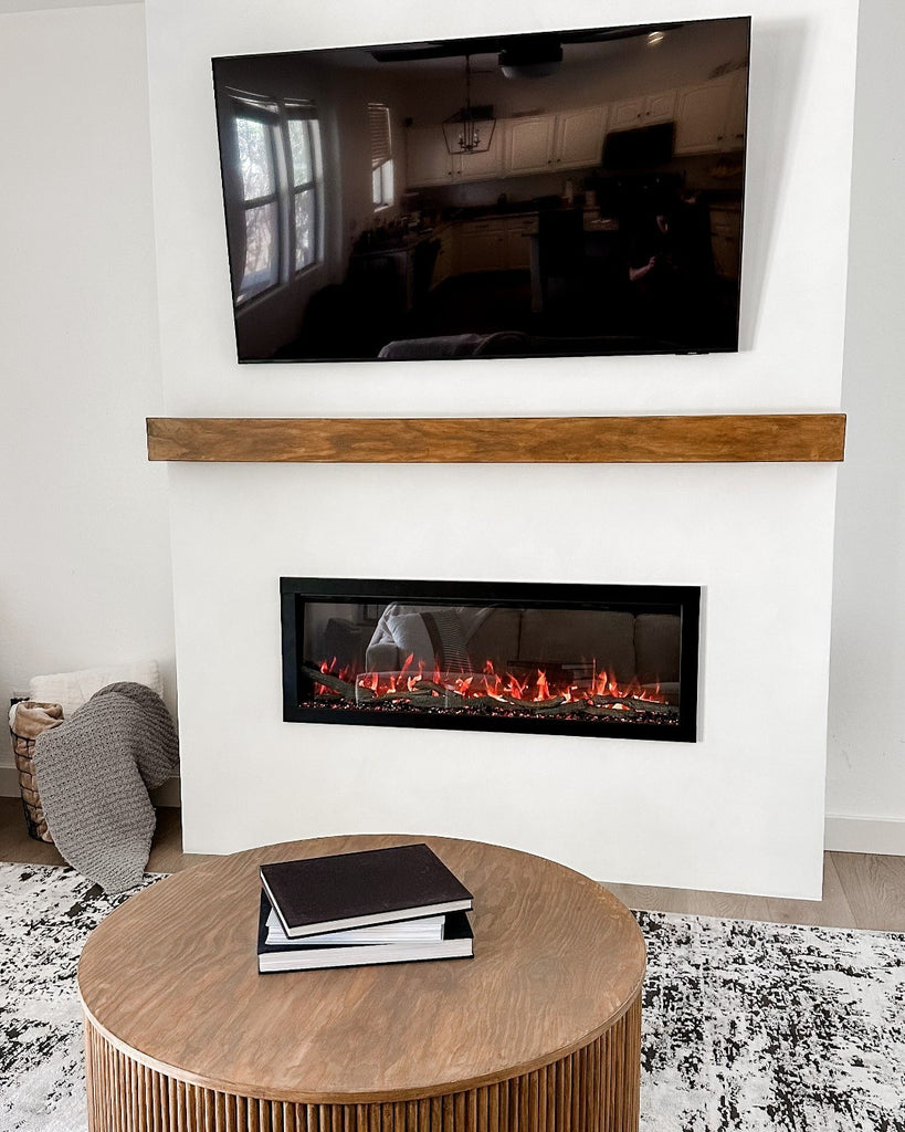 Linear fireplace with wood mantel shelf, television with black and white rug in the foreground.
