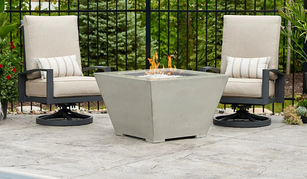 Square firepit on a patio with two lounge chairs.