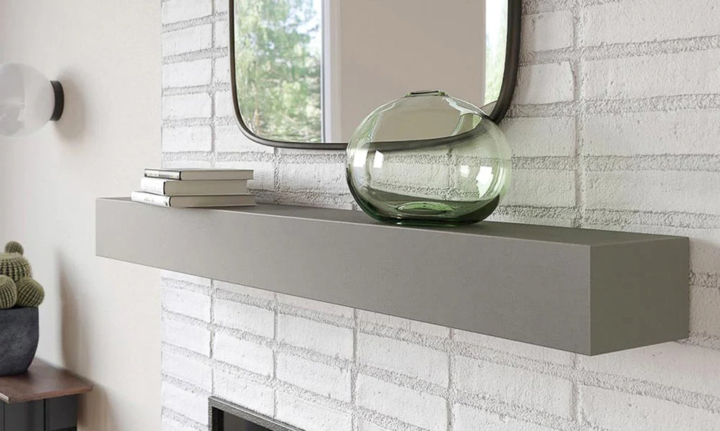 Concrete mantel in a wall with white brick and a mirror over the mantel.