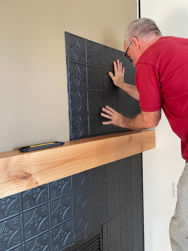 Person attaching tin tile panel to the wall.