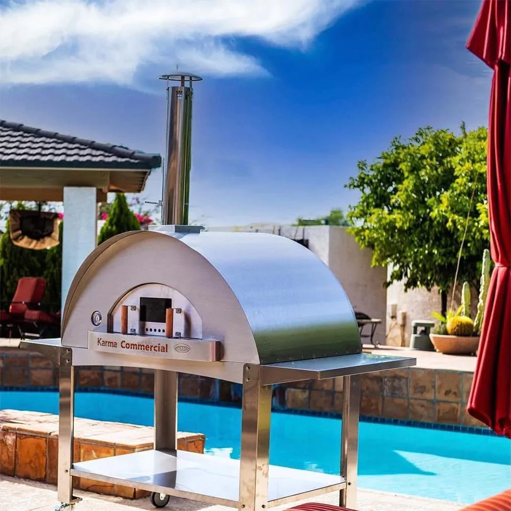 Freestanding metal pizza oven beside a pool.
