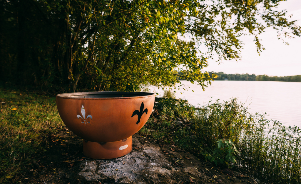 Round fire pit with fleur de lis cut outs on the side.