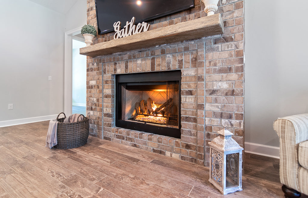 Gas fireplace with stacked stone surround and wood mantel.