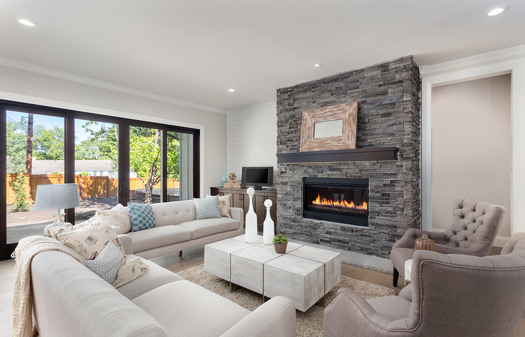 Large living room with white sectional couch and gray stone gas fireplace.
