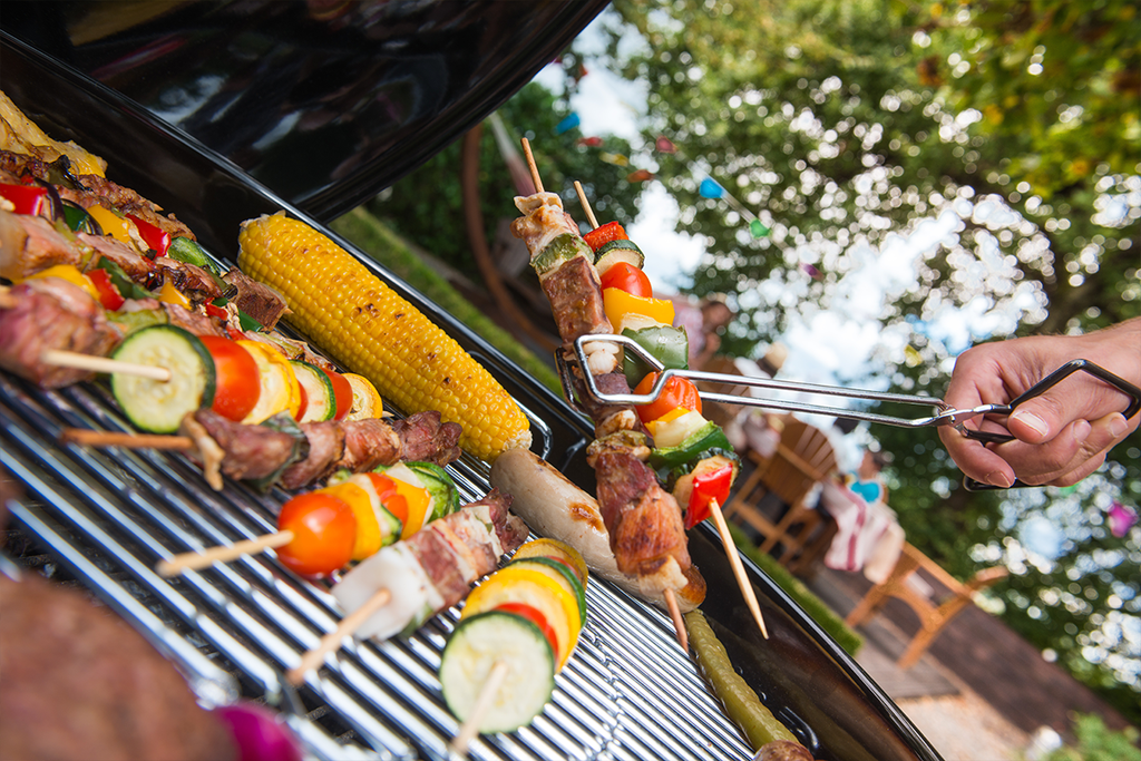 Person grilling skewers in a large backyard.