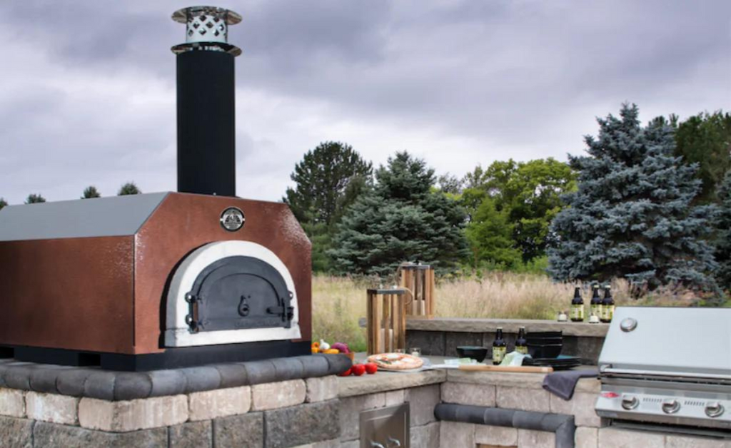 PIzza oven on a stone countertop in a backyard kitchen.