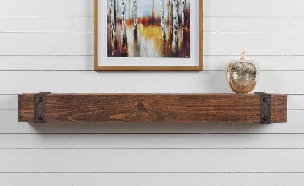 Wood mantel shelf against a white paneled wall with artwork overhead.