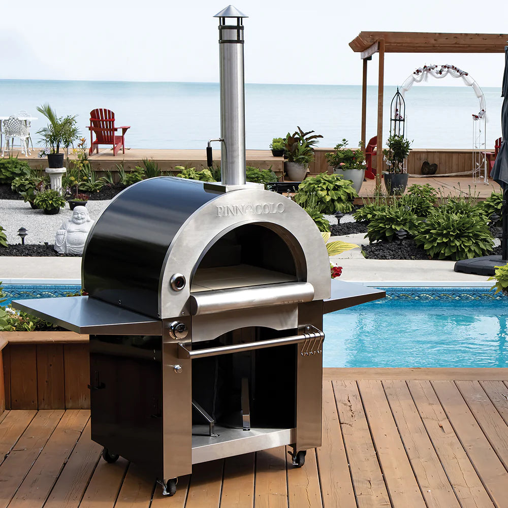 Freestanding pizza oven on a patio by a pool.