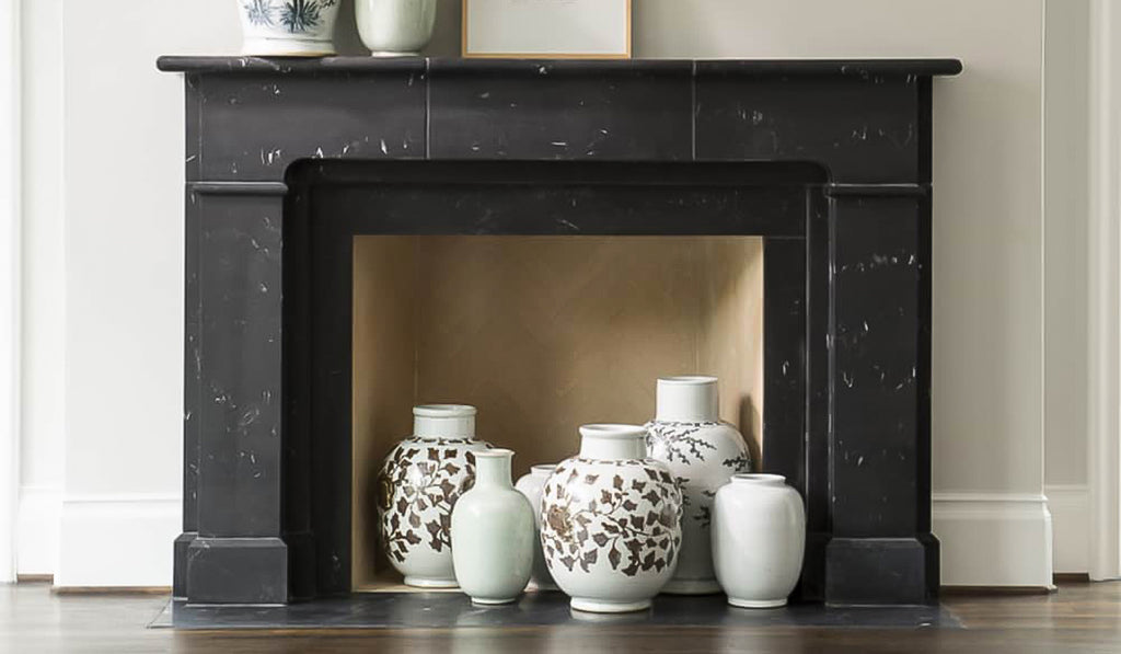 Black wood mantel with pottery as decoration.