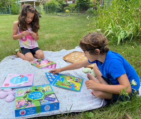 A boy and a girl (ages 6 and 7) enjoying a game of Party Time Bingo in their garden.