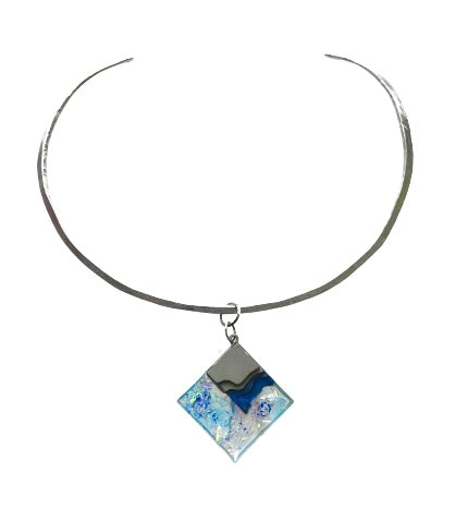 Aluminum neck wire with a diamond shaped resin pendant that features blue pigment, flakes of various glitters and a small section of cement in a wavy pattern, together invoking an ocean and a small island.