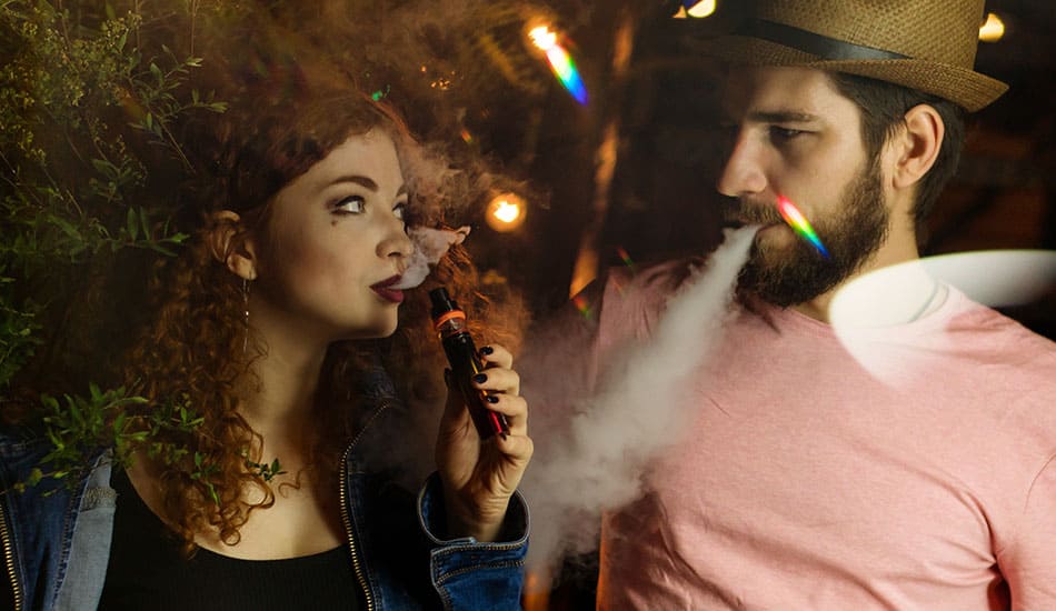 Couple looking at each other while sharing a vape kit.