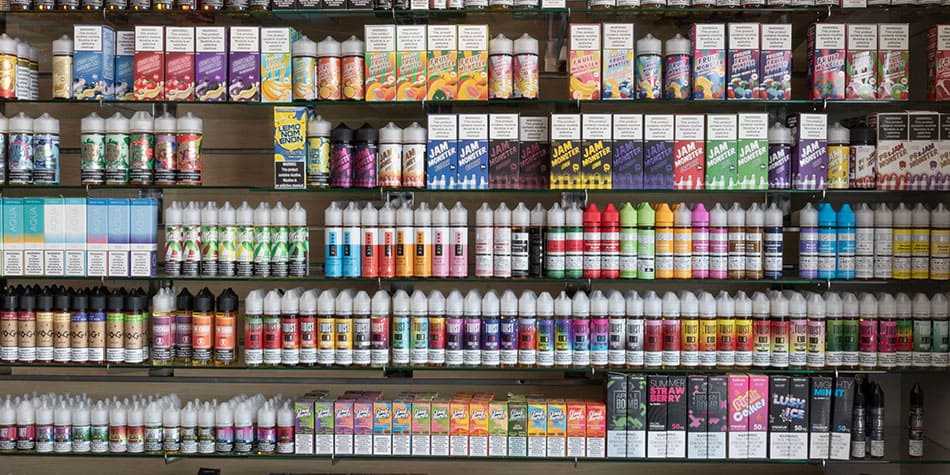 Wide selection of e-liquids displayed on a shop shelf.