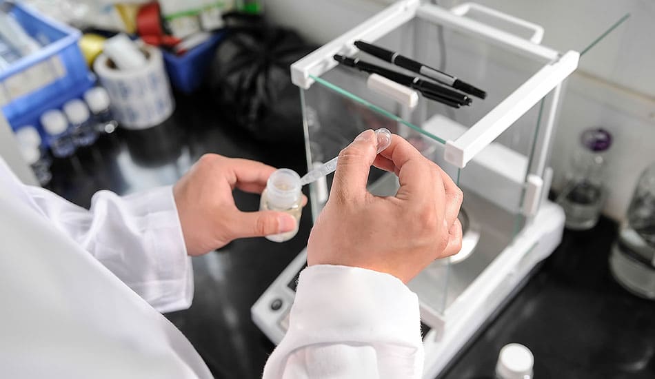 Person in a laboratory filling a bottle with liquid.