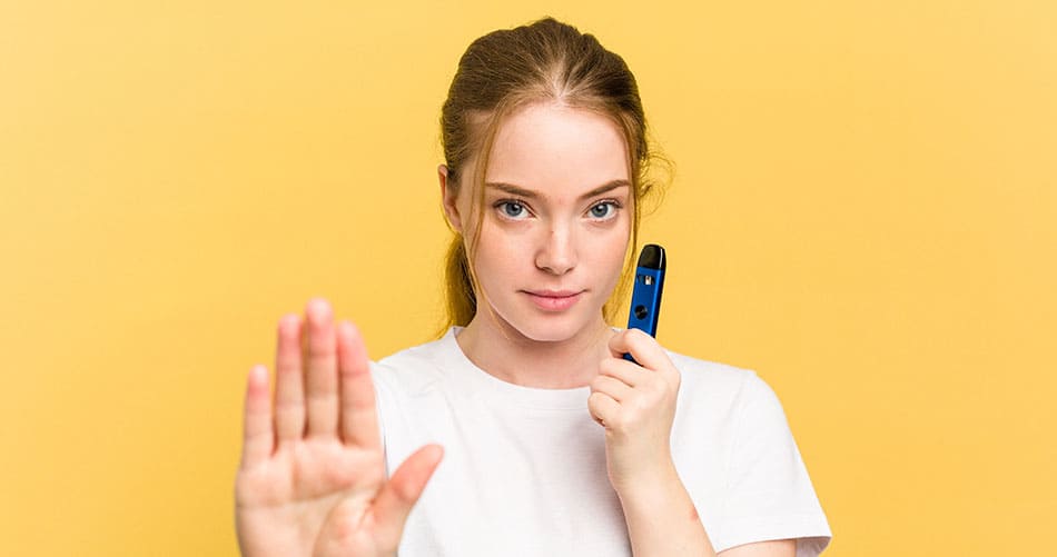 Girl holding a vape device in her left hand with her right hand pointed up in stop motion