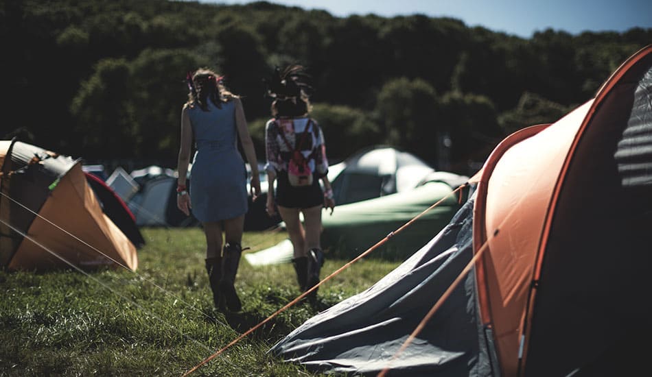 Women walking between tents at a festival.